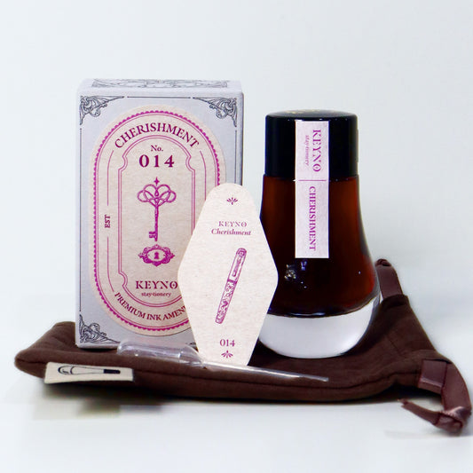 Dominant Industry Cherishment Key No. 14 fountain pen ink in a 25ml lightbulb-shaped glass bottle, muted pink ink visible inside next to its box and the official ink card. 