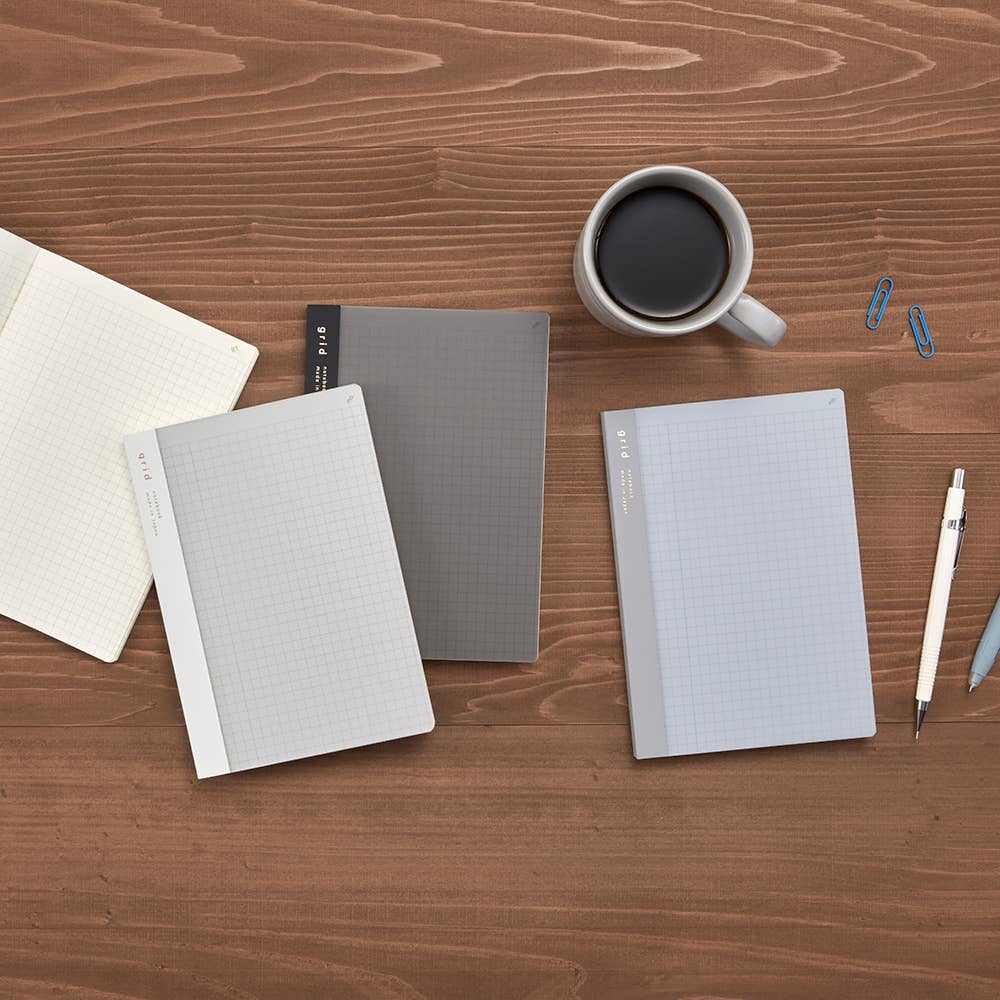 Isshoni notebooks on a wooden desk with a cup of coffee and pens