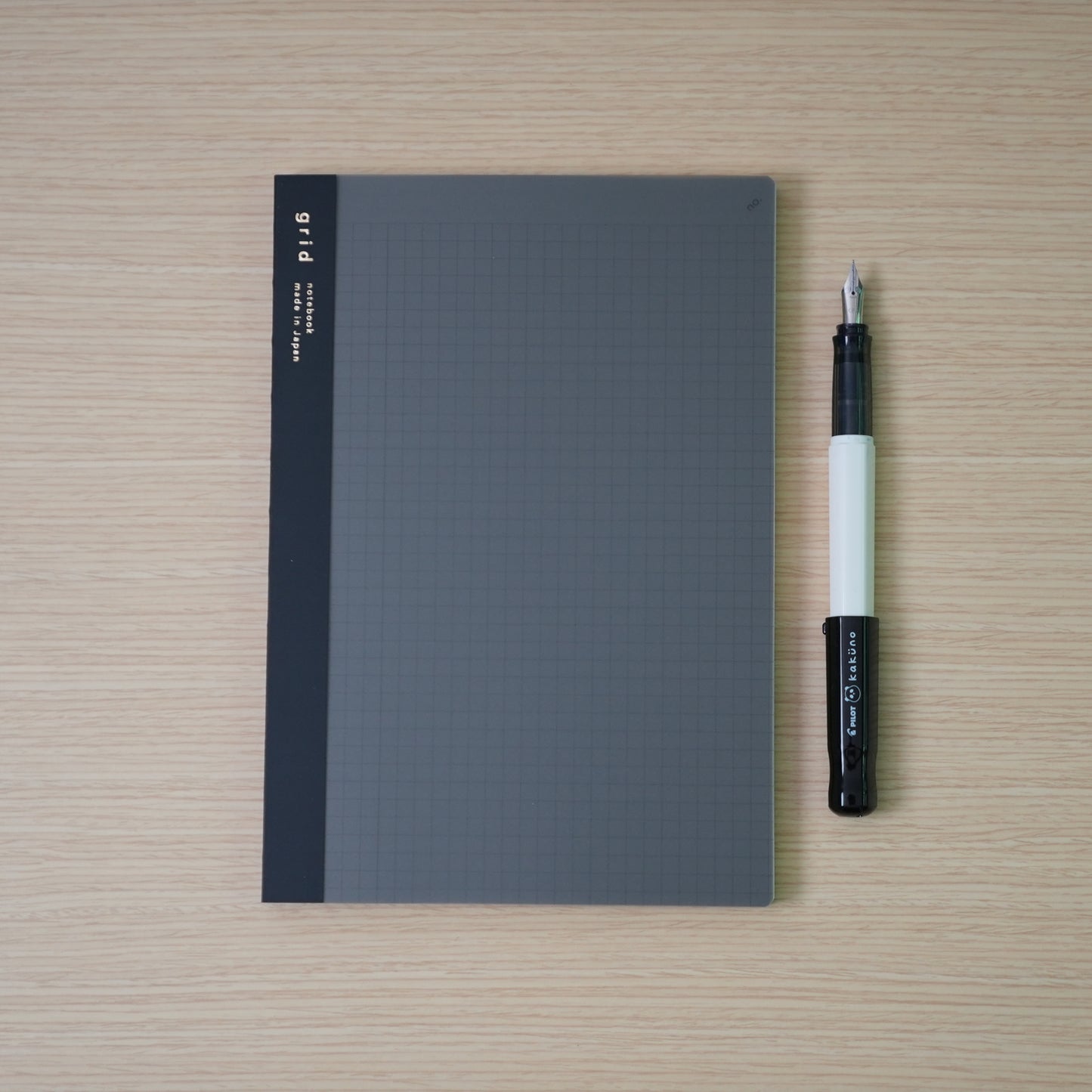 plain grid daigo isshoni. notebook and a black capped, white bodied panda pilot kakuno with 