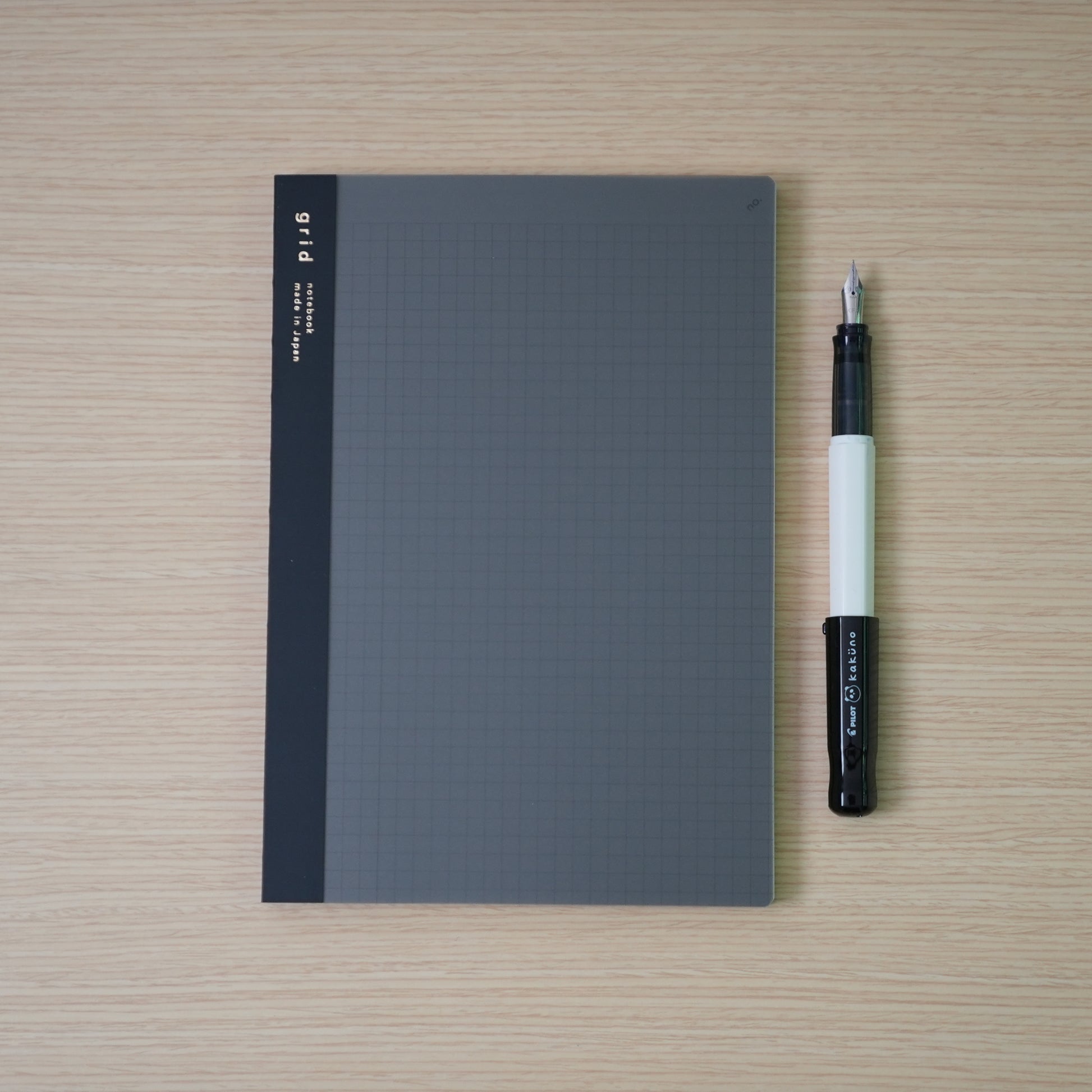 plain grid daigo isshoni. notebook and a black capped, white bodied panda pilot kakuno with 