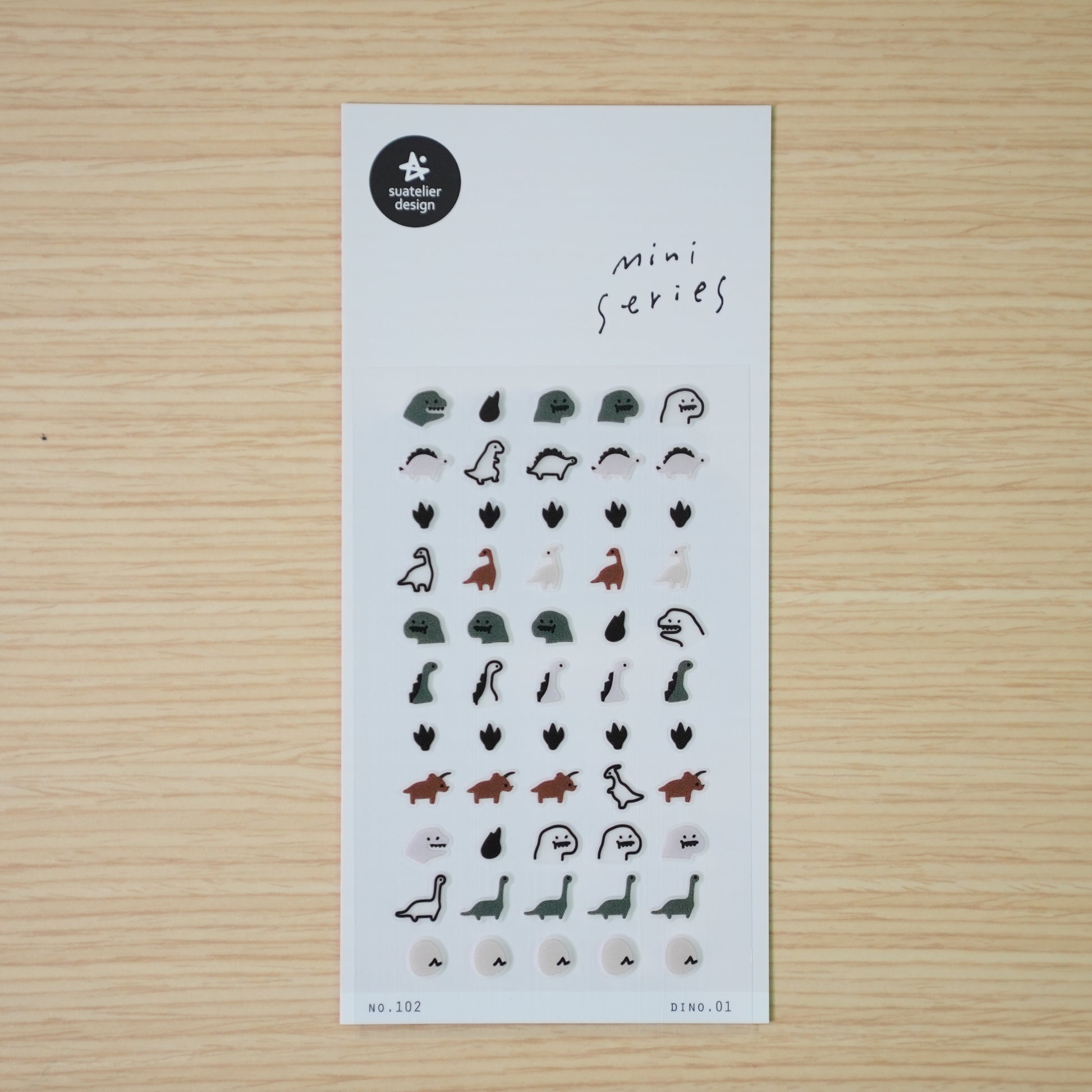 Suatelier mini PVC dinosaur stickers shown individually — stegosaurus, drop, long-neck, and ghost dino on wood desk