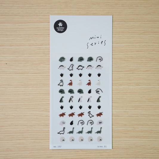 Suatelier mini PVC dinosaur stickers shown individually — stegosaurus, drop, long-neck, and ghost dino on wood desk