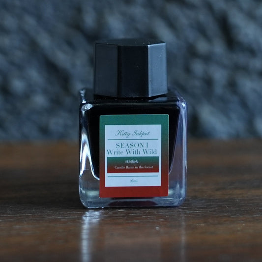 A bottle of kitty ink pot candle flame in the forest fountain pen ink on a desk