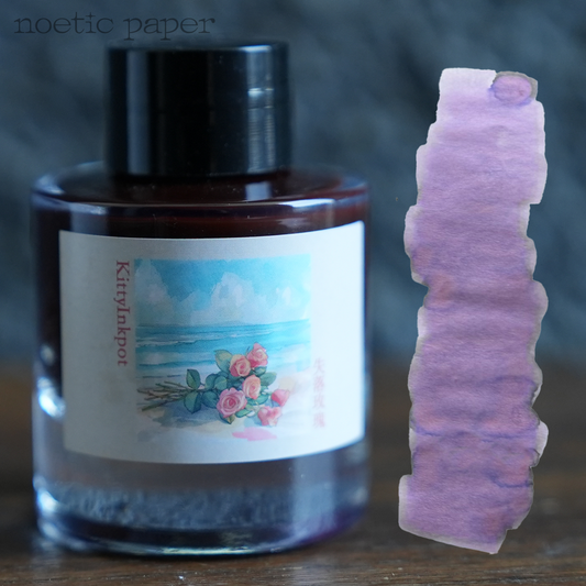 Kitty Inkpot lose rose on a desk with a swatch next to it. 