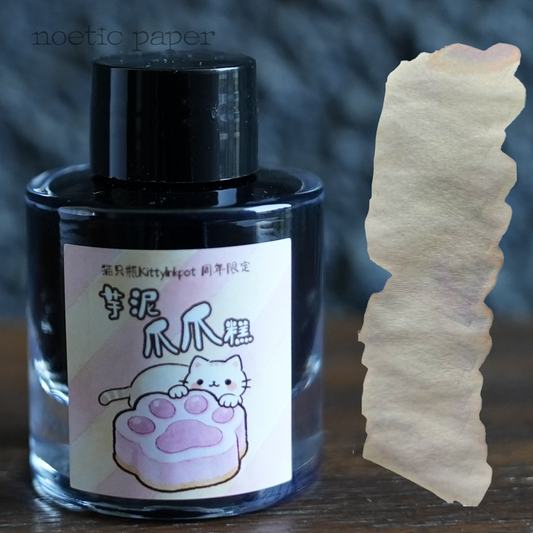 Kitty Inkpot taro taste paw cake on a desk with a swatch next to it. 
