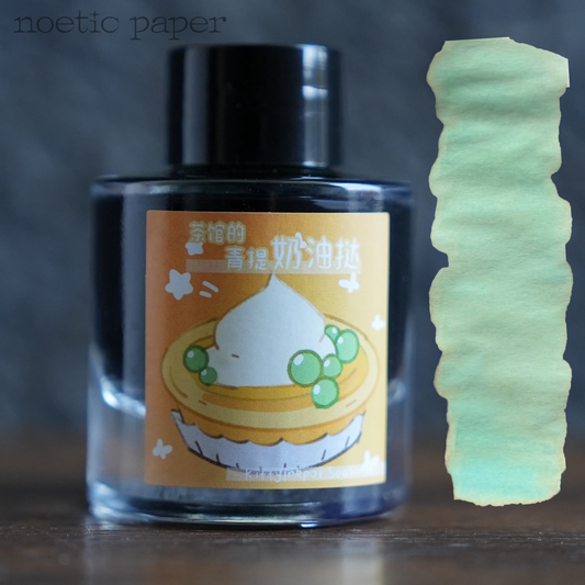 Kitty Inkpot The Green Tea Cream Cake in the Tea House on a desk with a swatch next to it. 