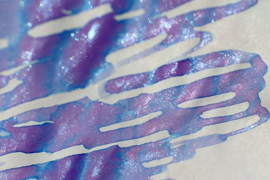Dominant Industry unicorn color-changing calligraphy ink in a 25ml bottle on a map and a swatch of the ink